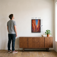 Canyon Riders framed print, 16x24 inch, shown to true scale beside a man in a black frame above a sideboard