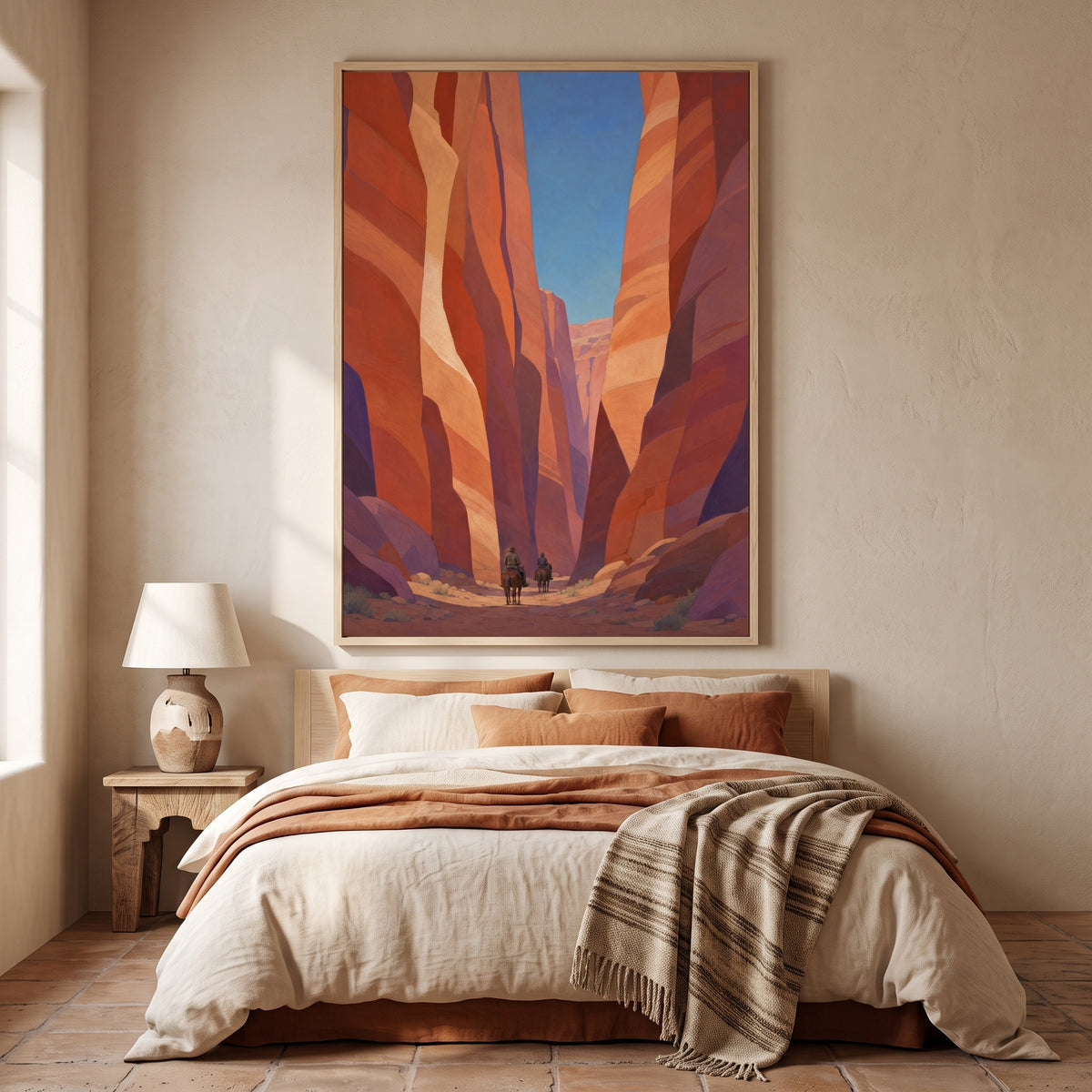 Canyon Riders framed print in a light wood frame above a bed in a warm southwestern bedroom