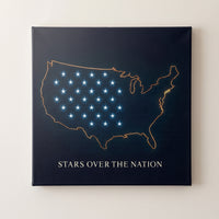 Stars over the Nation – gold outline map of the United States with blue stars on navy, patriotic canvas wall art on a linen white wall