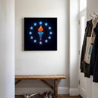 Torch of Liberty – neon torch inside a ring of blue stars on black, patriotic canvas wall art above a wooden bench in a hallway